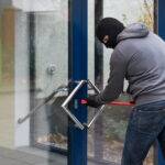 Man Using Crowbar To Open Glass Door